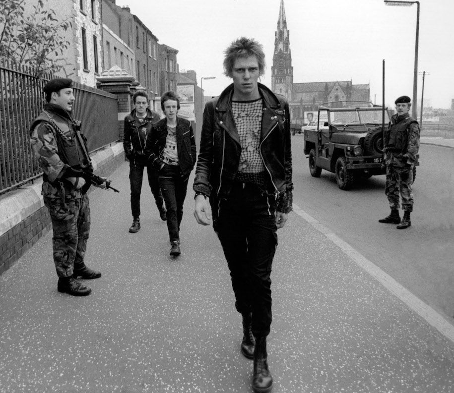 Paul Simonon (vorne), Nicky „Topper“ Headon und Joe Strummer (hinten) mit zwei britischen Soldaten auf der Crumlin Road, Belfast, Oktober 1977, Quelle: Mit freundlicher Genehmigung des Fotografen Adrian Boot.
