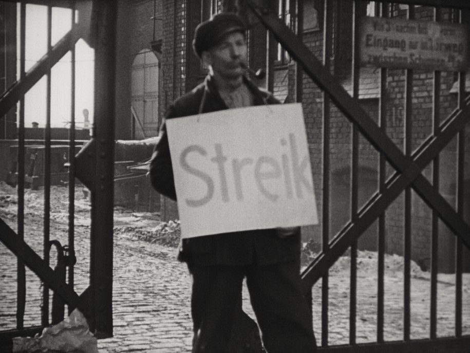 Person mit Streikschild, Filmstill aus Brüder von Werner Hochbaum (1929), Quelle: Deutsche Kinemathek, ©Deutsche Kinemathek / Filmarchiv Austria.