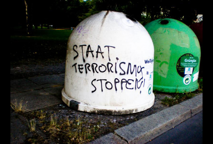 Glaßmülltonne mit der Aufschrift "Staat Terrorismus Stoppen"