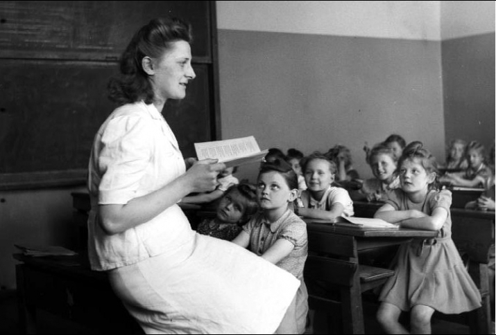 Lehrerin lesend vor einer Grundschulklasse