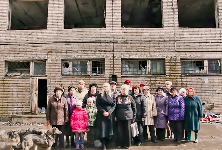 Menschengruppe vor einem maroden Gebäude, die einen Antrag an Putin stellen