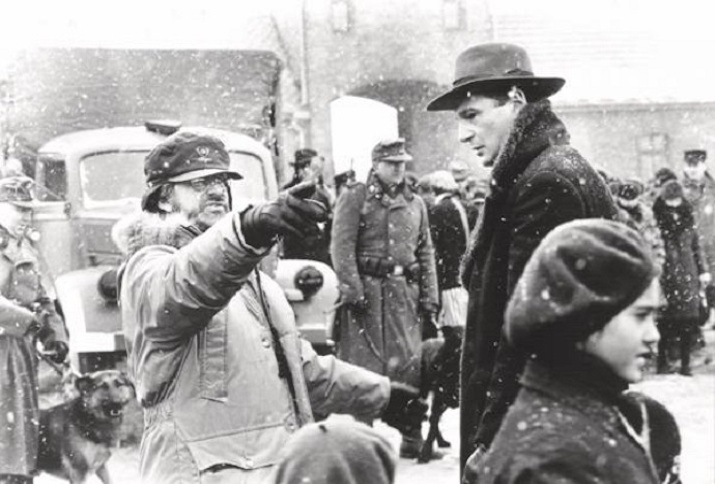 Film Still aus Schindlers Liste das Oskar Schindler in seiner Fabrik zu den jüdischen Arbeiter*innen sprechend zeigt