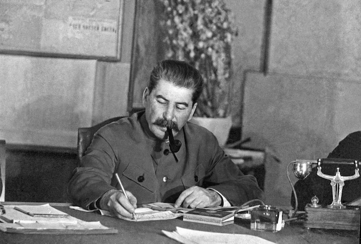 Joseph Stalin sitzt Pfeife rauchend an seinem Schreibtisch