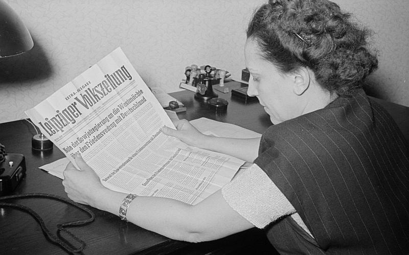 Porträt von Margarete Däumichen, die eine am 11. März 1952 zur Stalin-Note erschienene Sonderausgabe der Leipziger Volkszeitung liest. 
