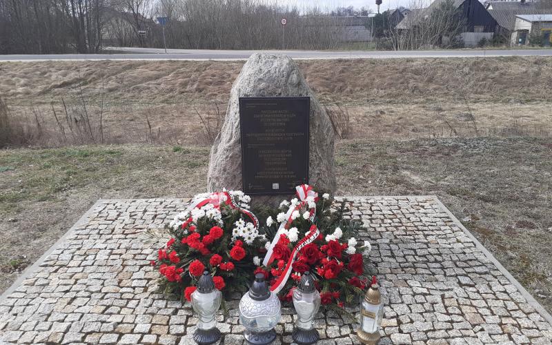 Denkmal an dem Ort der ehemaligen Bahnhofsstation im Dorf Treblinka, 31. März 2026. Die Kränze wurden vom Pilecki Institut (Witold Pilecki Institute of Solidarity and Courage) und vom Bürgermeister und den Bewohnern der Gemeinde Małkinia gestiftet; rechts eine goldene Kerze mit der goldenen Inschrift „Treblinka Museum – wir erinnern” 