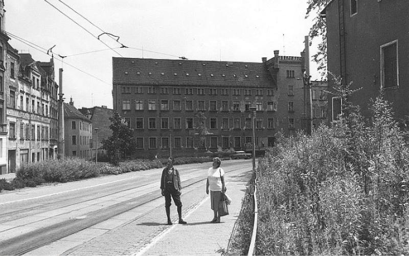Schwarz-weiße Fotografie von einem älteren Ehepaar, das auf einer Straße vor einem verlassenen Gebäude steht