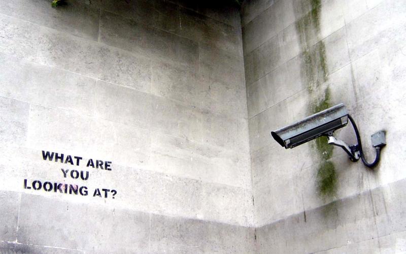 Kamera ist auf eine leere Wand ausgerichtet, auf der "What are you looking at?" steht
