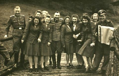 Nazi officers and female auxiliaries pose on a wooden bridge in Solahuette