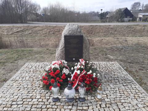 Denkmal an dem Ort der ehemaligen Bahnhofsstation im Dorf Treblinka, 31. März 2026. Die Kränze wurden vom Pilecki Institut (Witold Pilecki Institute of Solidarity and Courage) und vom Bürgermeister und den Bewohnern der Gemeinde Małkinia gestiftet; rechts eine goldene Kerze mit der goldenen Inschrift „Treblinka Museum – wir erinnern” 