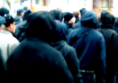 Rückansicht von Menschen mit schwarzen Kapuzen beim Nazi-Aufmarsch und Gegendemo Rückansicht von Menschen mit schwarzen Kapuzen beim Nazi-Aufmarsch und Gegendemo