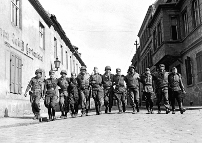 Begegnung amerikanische und sowjetischer Soldaten Amerikanische und sowjetische Soldaten laufen Arm in Arm in einer Reihe auf einer Straße im deutschen Torgau