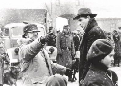 Film Still aus Schindlers Liste Film Still aus Schindlers Liste das Oskar Schindler in seiner Fabrik zu den jüdischen Arbeiter*innen sprechend zeigt