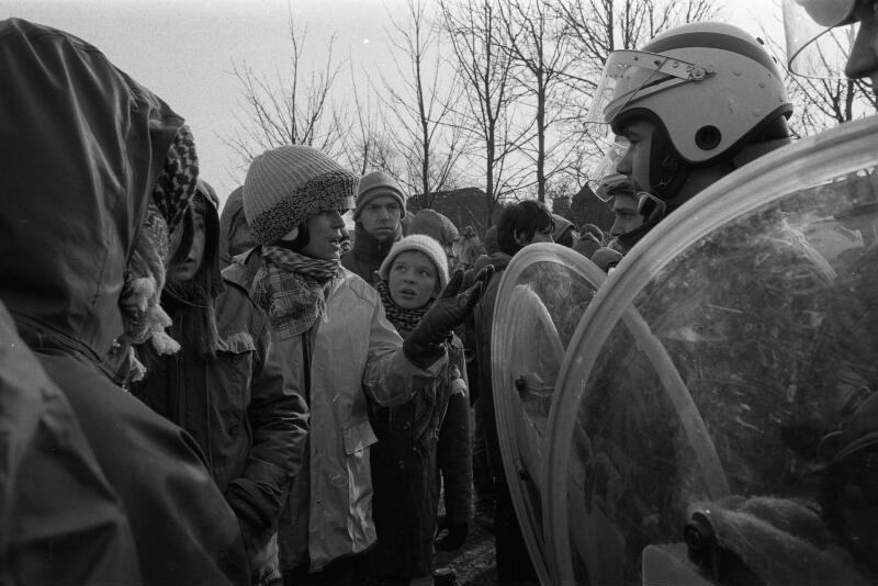 Großdemonstration gegen Bau eines Atomkraftwerkes in Brokdorf, Demonstranten im Gespräch mit Einsatzkräften der Polizei, Polizist mit Schild und Schutzhelm, 28. Februar 1981.