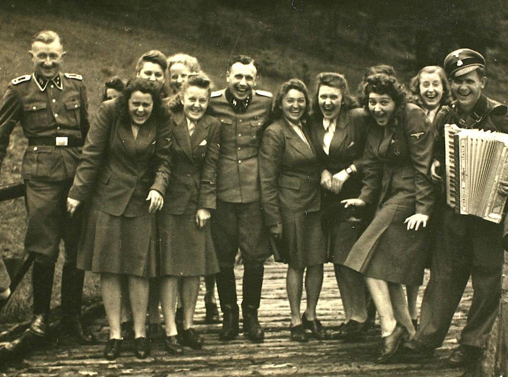 Nazi officers and female auxiliaries pose on a wooden bridge in Solahuette