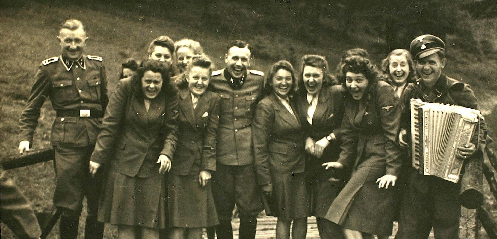 Nazi officers and female auxiliaries pose on a wooden bridge in Solahuette