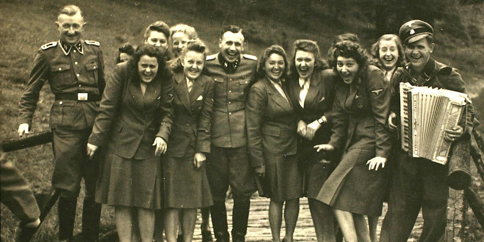 Nazi officers and female auxiliaries pose on a wooden bridge in Solahuette
