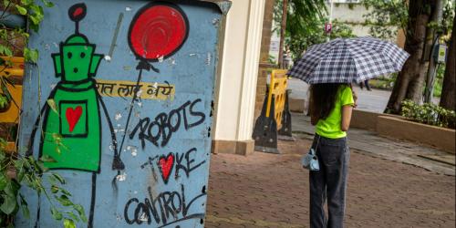 Links ein Graffiti mit der Aufschrift "Robots take control", rechts eine junge Frau mit Regenschirm
