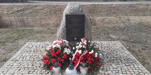 Denkmal an dem Ort der ehemaligen Bahnhofsstation im Dorf Treblinka, 31. März 2026. Die Kränze wurden vom Pilecki Institut (Witold Pilecki Institute of Solidarity and Courage) und vom Bürgermeister und den Bewohnern der Gemeinde Małkinia gestiftet; rechts eine goldene Kerze mit der goldenen Inschrift „Treblinka Museum – wir erinnern” 