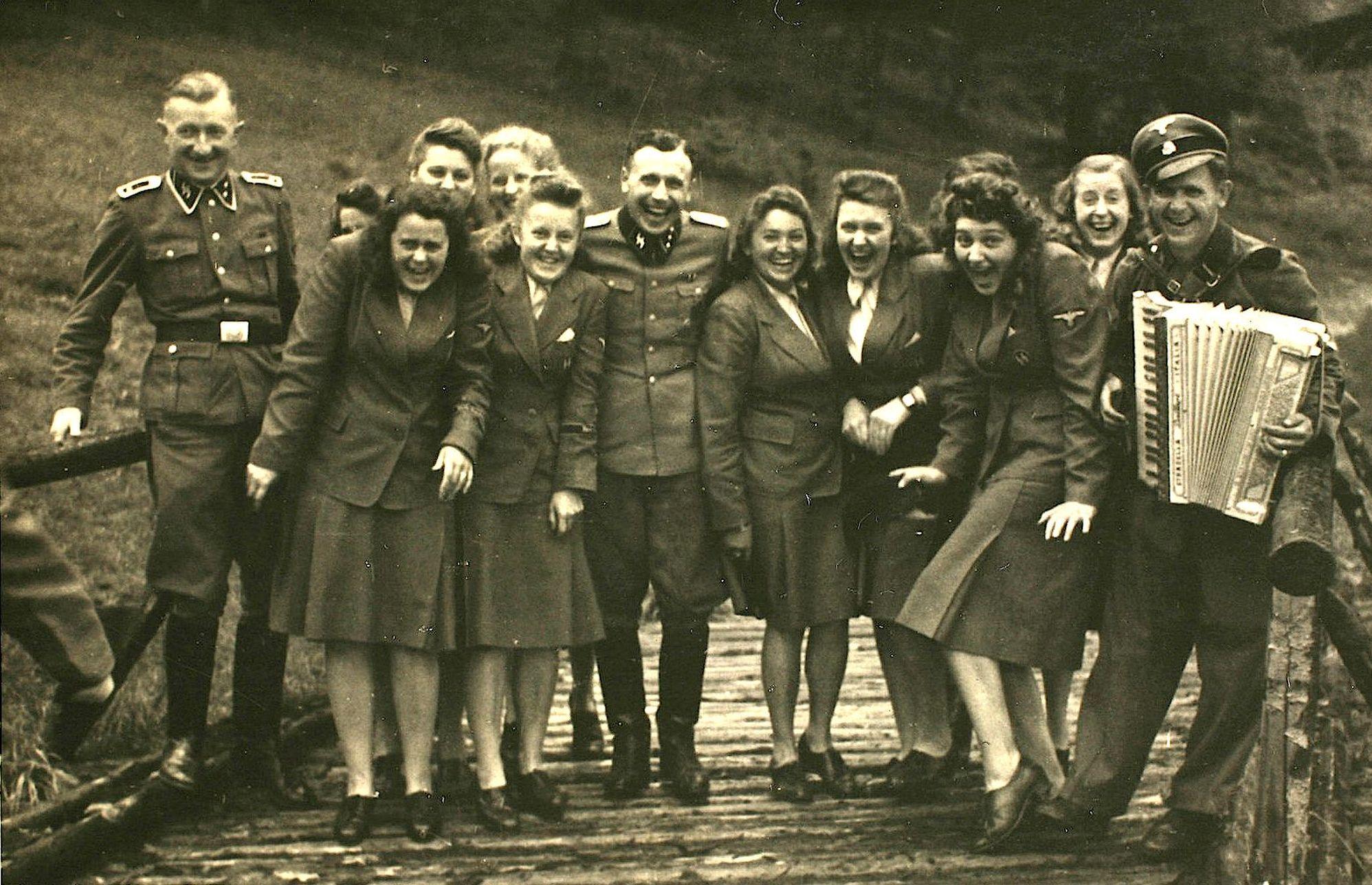Nazi officers and female auxiliaries pose on a wooden bridge in Solahuette