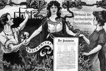 Das Motiv entstand 1909 und zeigt Arbeiterin und Arbeiter sich in Solidarität die Hände reichend. Im Hintergrund rauchen die Fabrikschlote, im Vordergrund ist die Titelseite der Zeitung "Der Proletarier" abgebildet